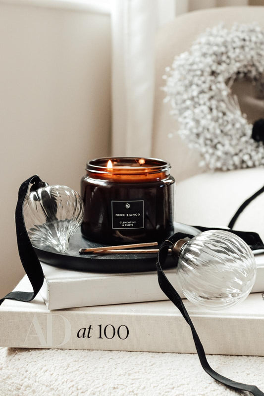 dual wick amber candle on a black tray with glass baubles
