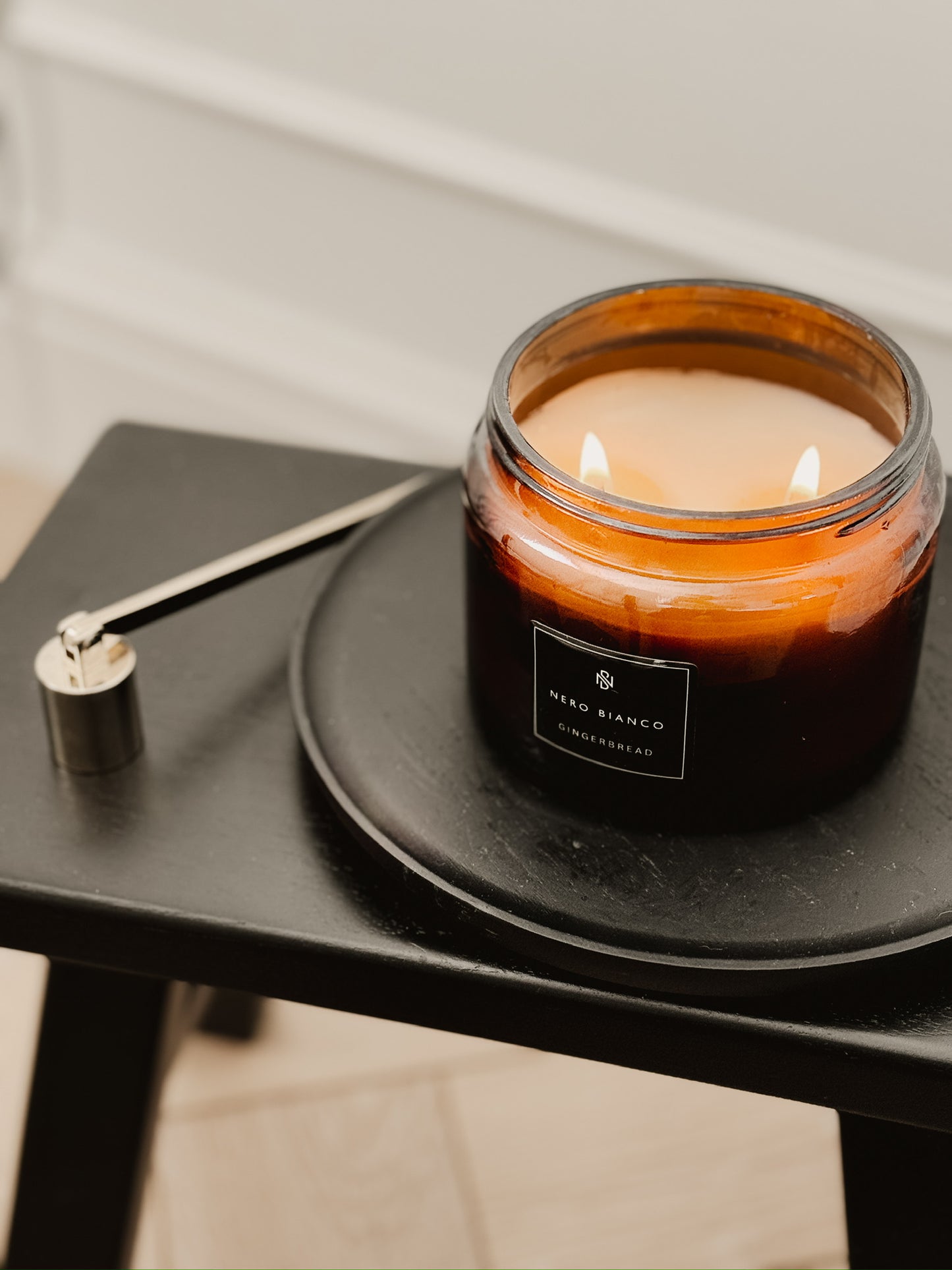 Candle in a glass jar with a black label on a dark surface.