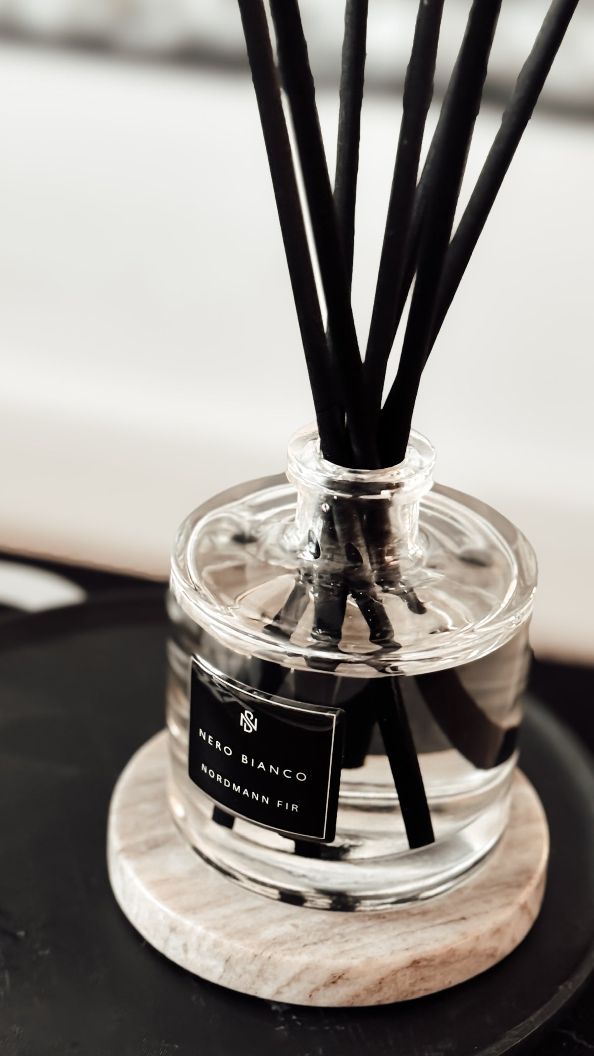 Nero Bianco diffuser with black sticks on a marble coaster