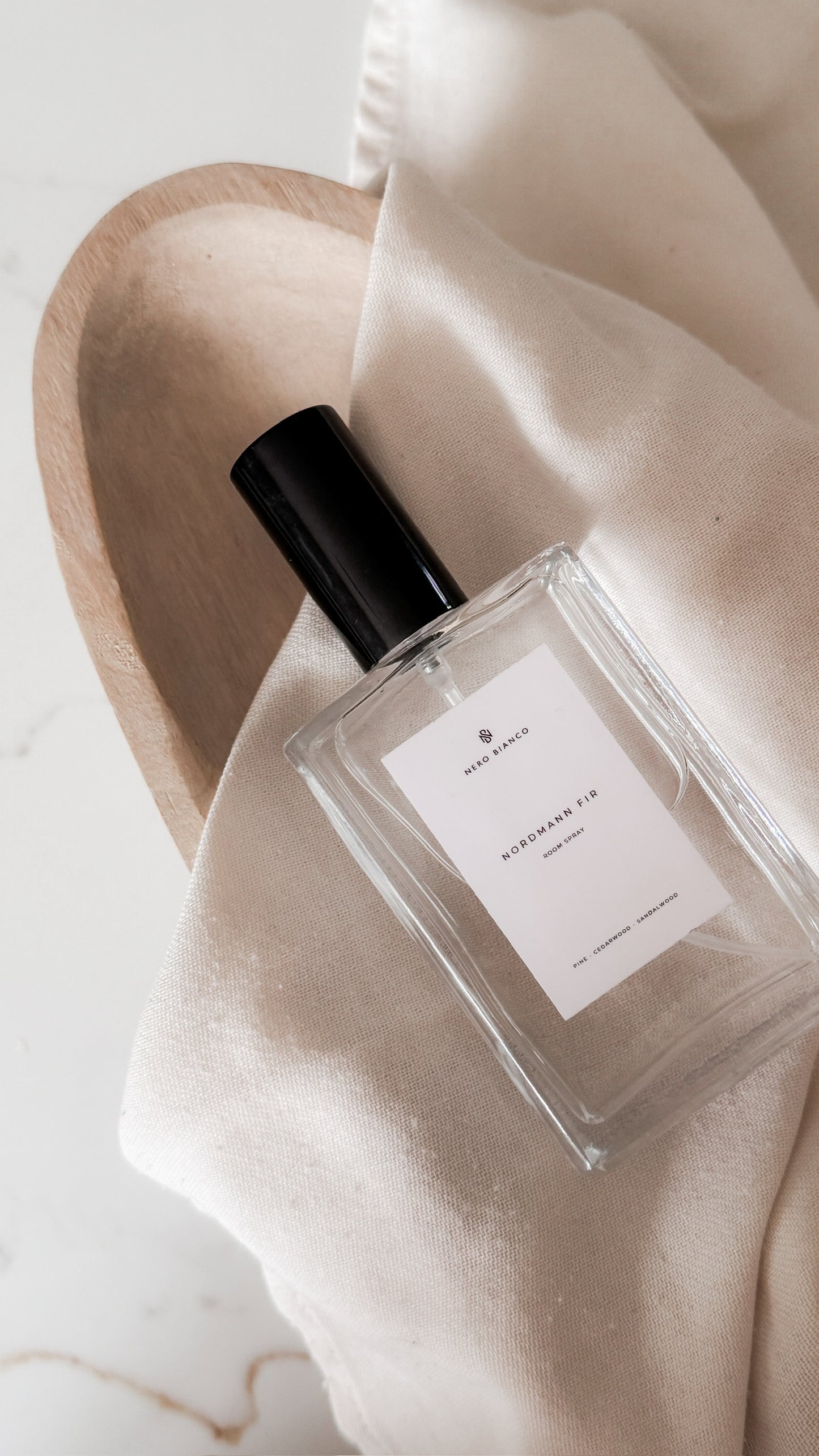 Perfume bottle with a black cap on a beige fabric background