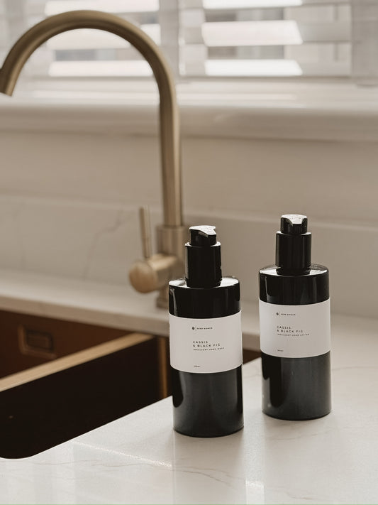 hand wash and hand lotion in black bottles with white labels on a kitchen counter.