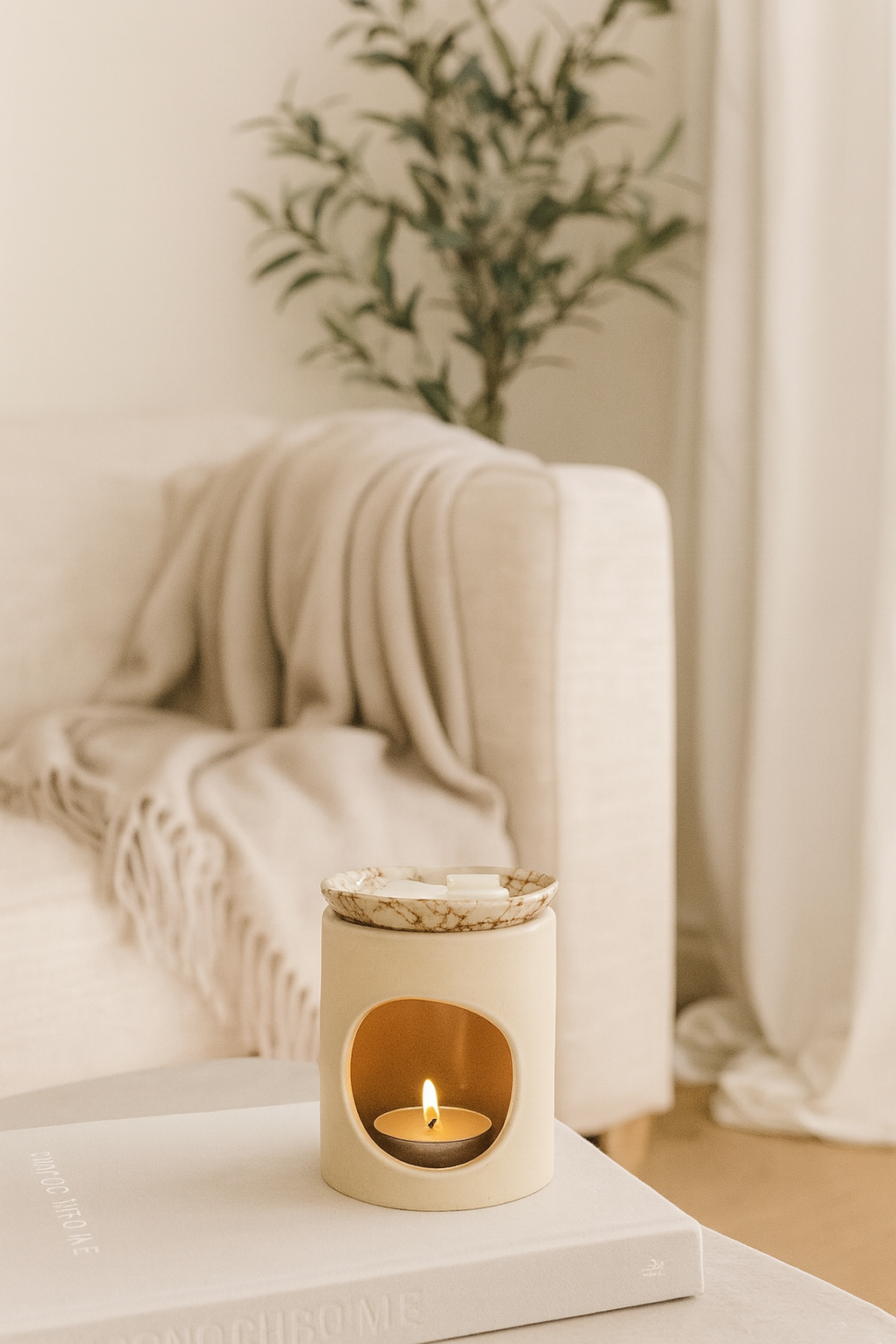 cream wax melt burner on a coffee table with a blurred background and olive tree