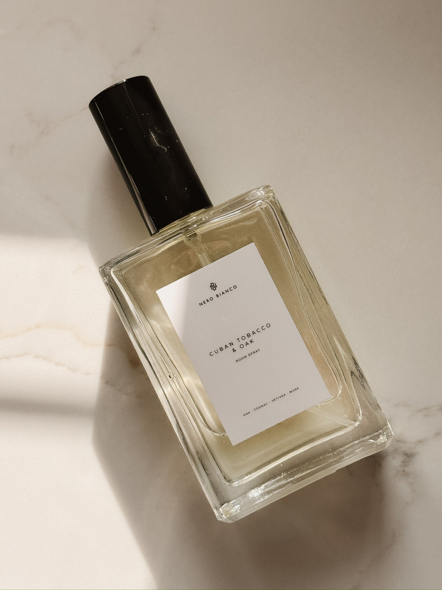 cuban tobacco and oak room spray in rectangle bottle with a black cap on a marble surface