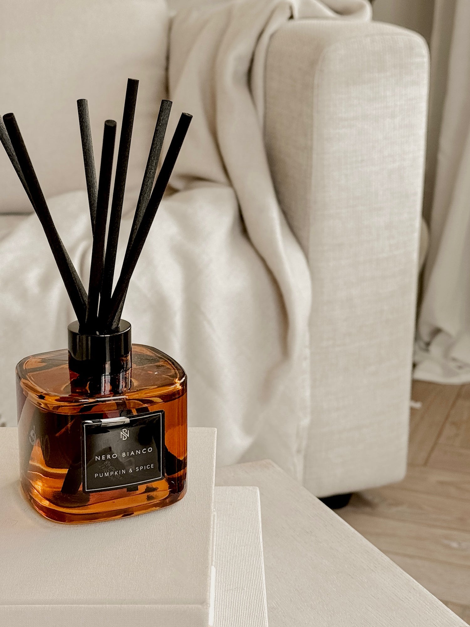 square amber reed diffuser in pumpkin and spice scent in a neutral living room