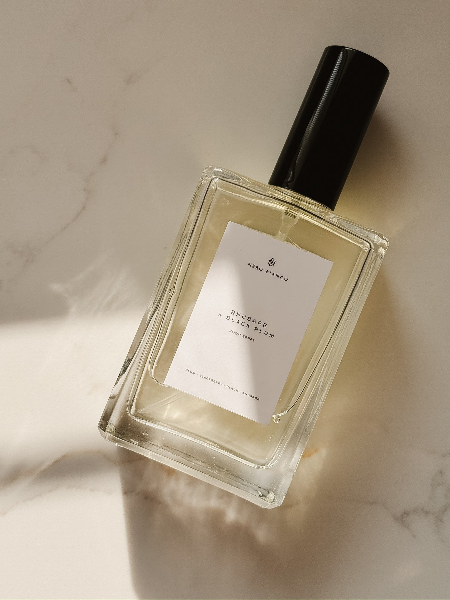 rhubarb and black plum room spray in rectangle glass bottle with a black cap on a marble surface