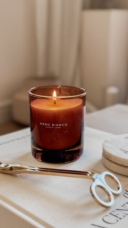 Nero Bianco candle burning on a newspaper with a blurred background