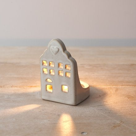 Ceramic house-shaped lantern with small lights on a wooden surface
