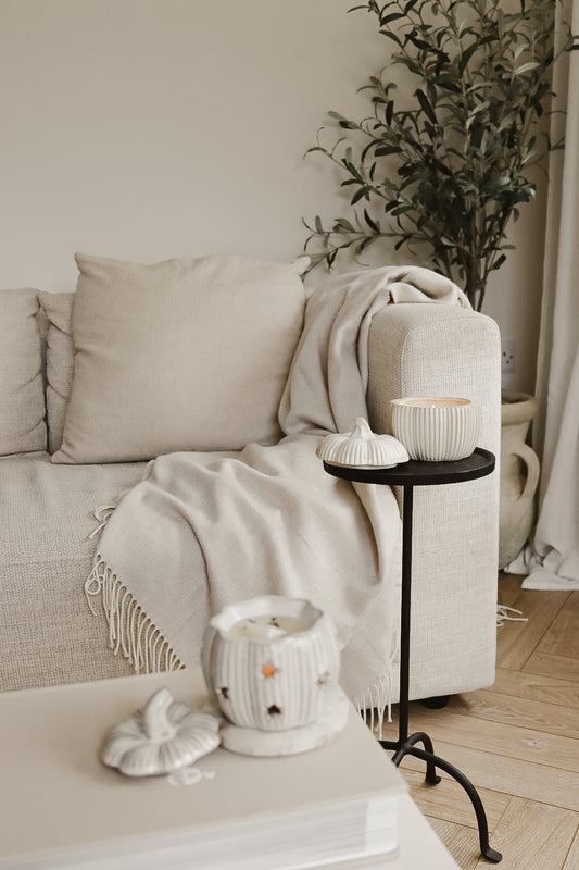 PUMPKIN CANDLE AND PUMPKIN WAX MELT BURNER IN A NEUTRAL LIVING ROOM WITH OLIVE TREE