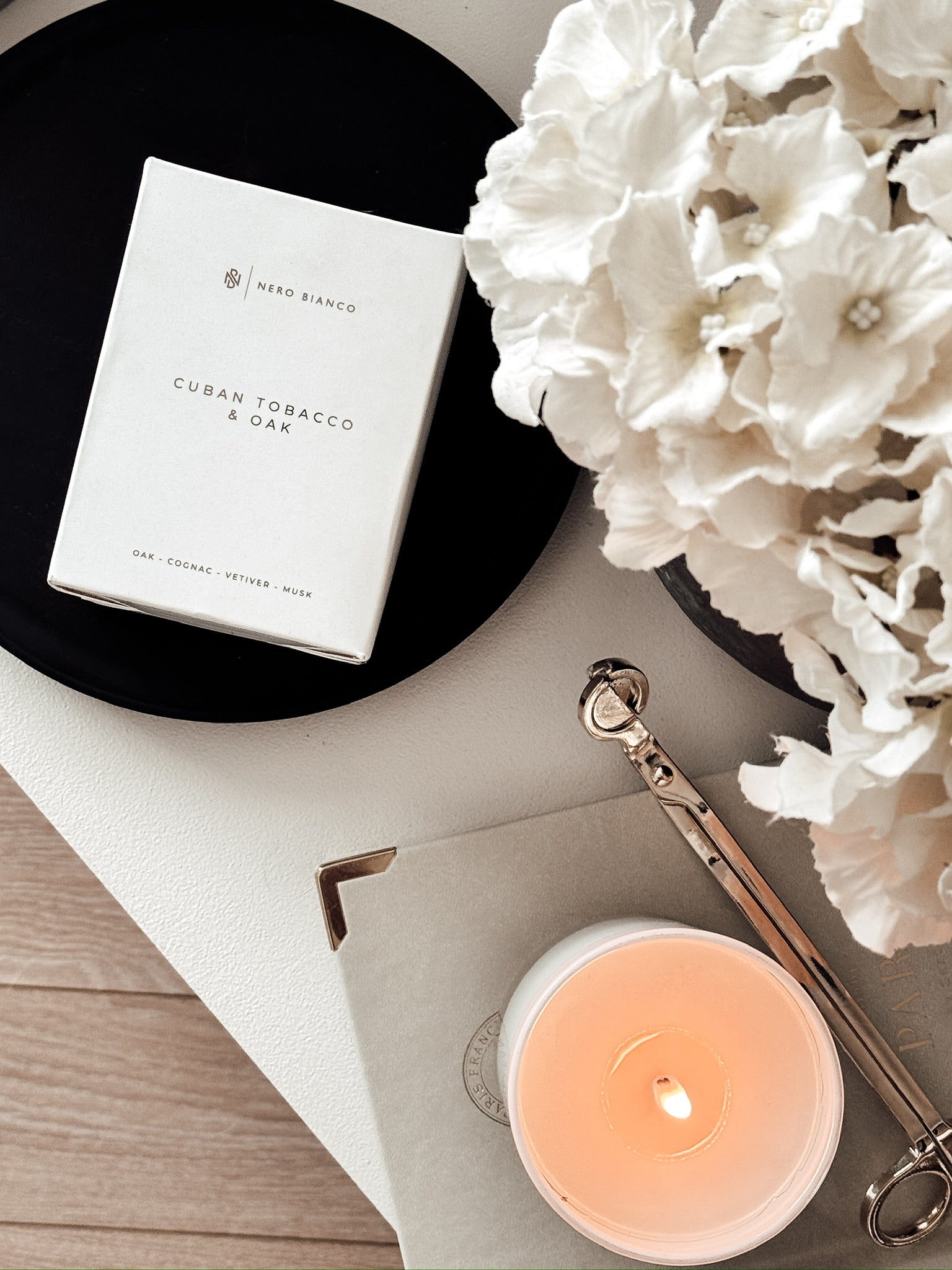 white vegan candle lit alongside the box for scent cuban tobacco & oak