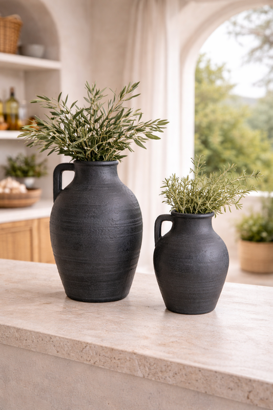 Two black ceramic jugs with plants on a kitchen counter