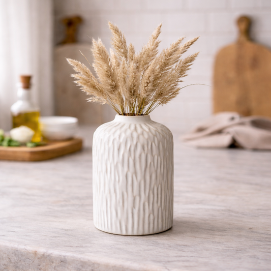 White textured vase with dried plants on a marble surface