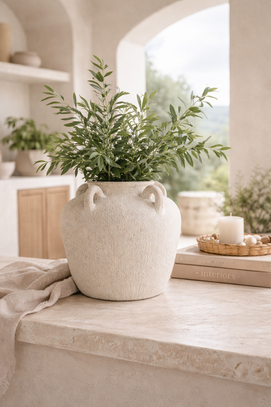 White vase with green plant on a wooden surface in a bright room