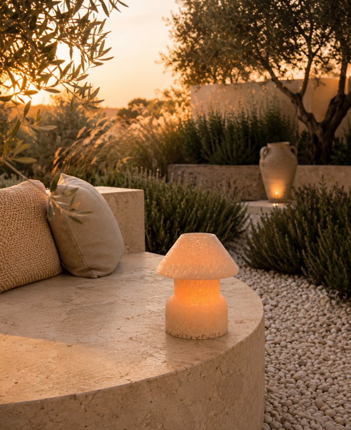 Outdoor setting with a table lamp on a stone surface, surrounded by natural elements and a sunset.
