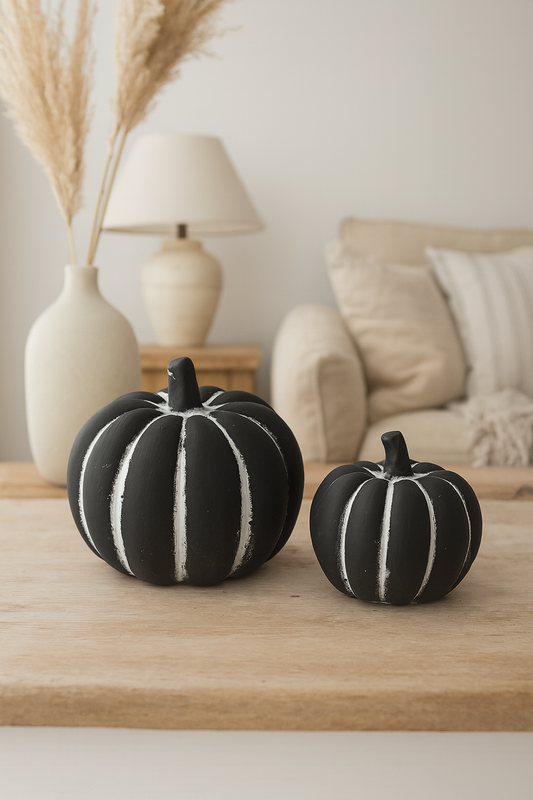 Two black pumpkins with white stripes on a wooden surface in a cozy living room.