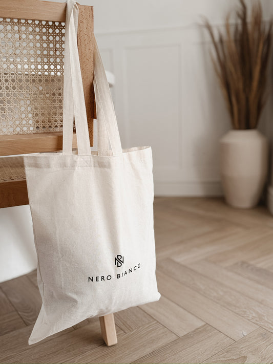 Beige tote bag with Nero Bianco logo on a wooden chair