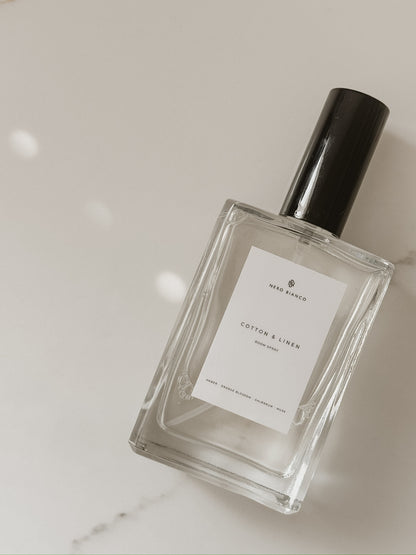 cotton and linen room spray in glass bottle with black cap on a light gray background