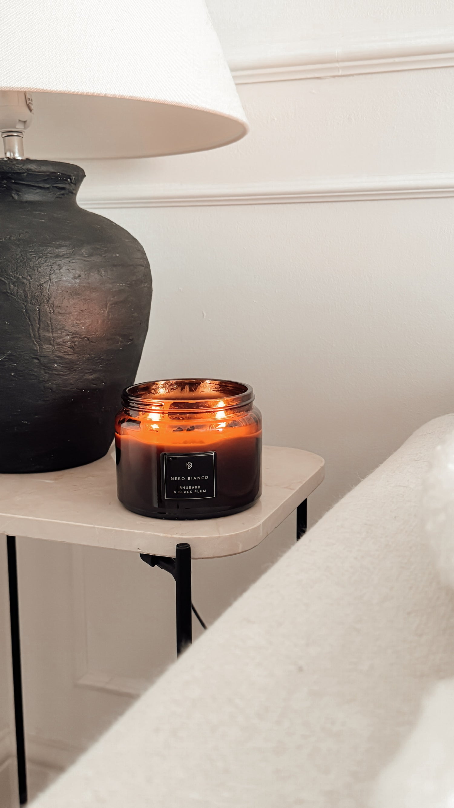 Candle on a small table next to a lamp in a cozy room setting