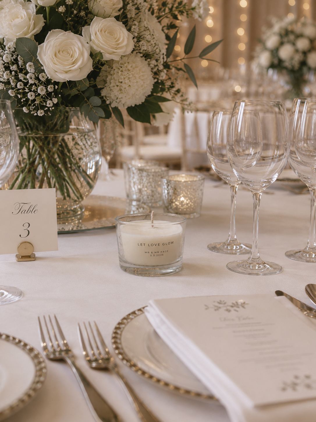 Elegant table setting with flowers, candles, and silverware in a formal dining setting.
