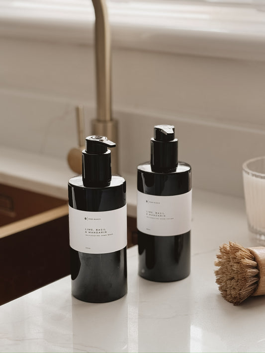 lime basil and mandarin hand wash and hand lotion in black bottles with white labels on a kitchen sink.