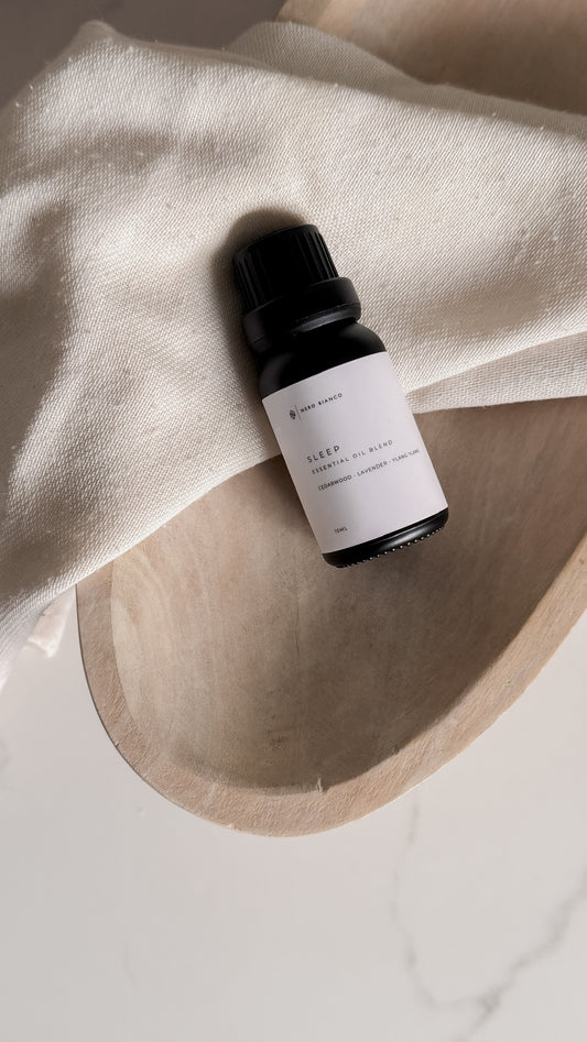 Bottle of essential oil labeled 'Sleep' on a light fabric background