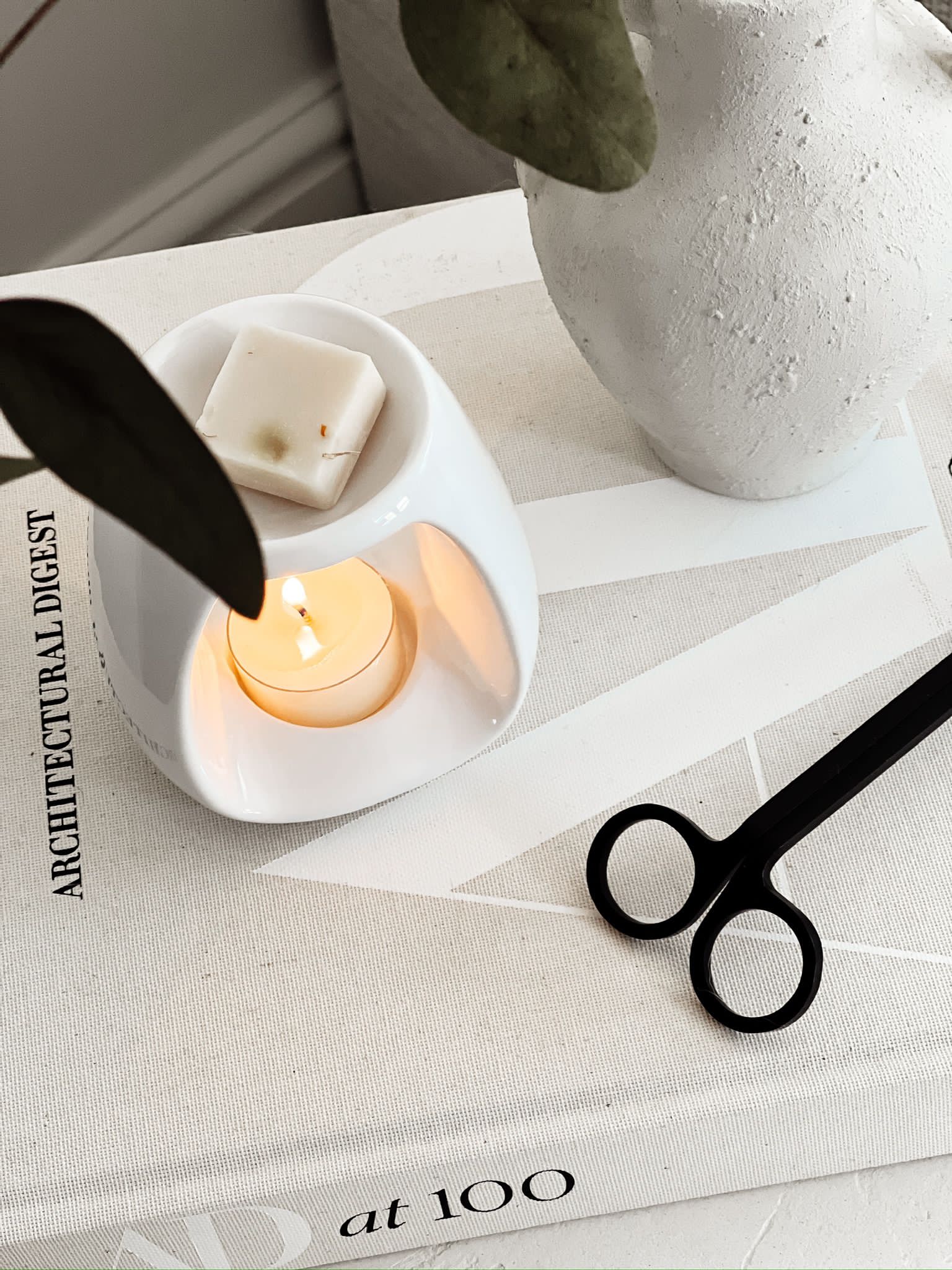 soy wax melt burning in a white wax melt burner styled with candle wick trimmer
