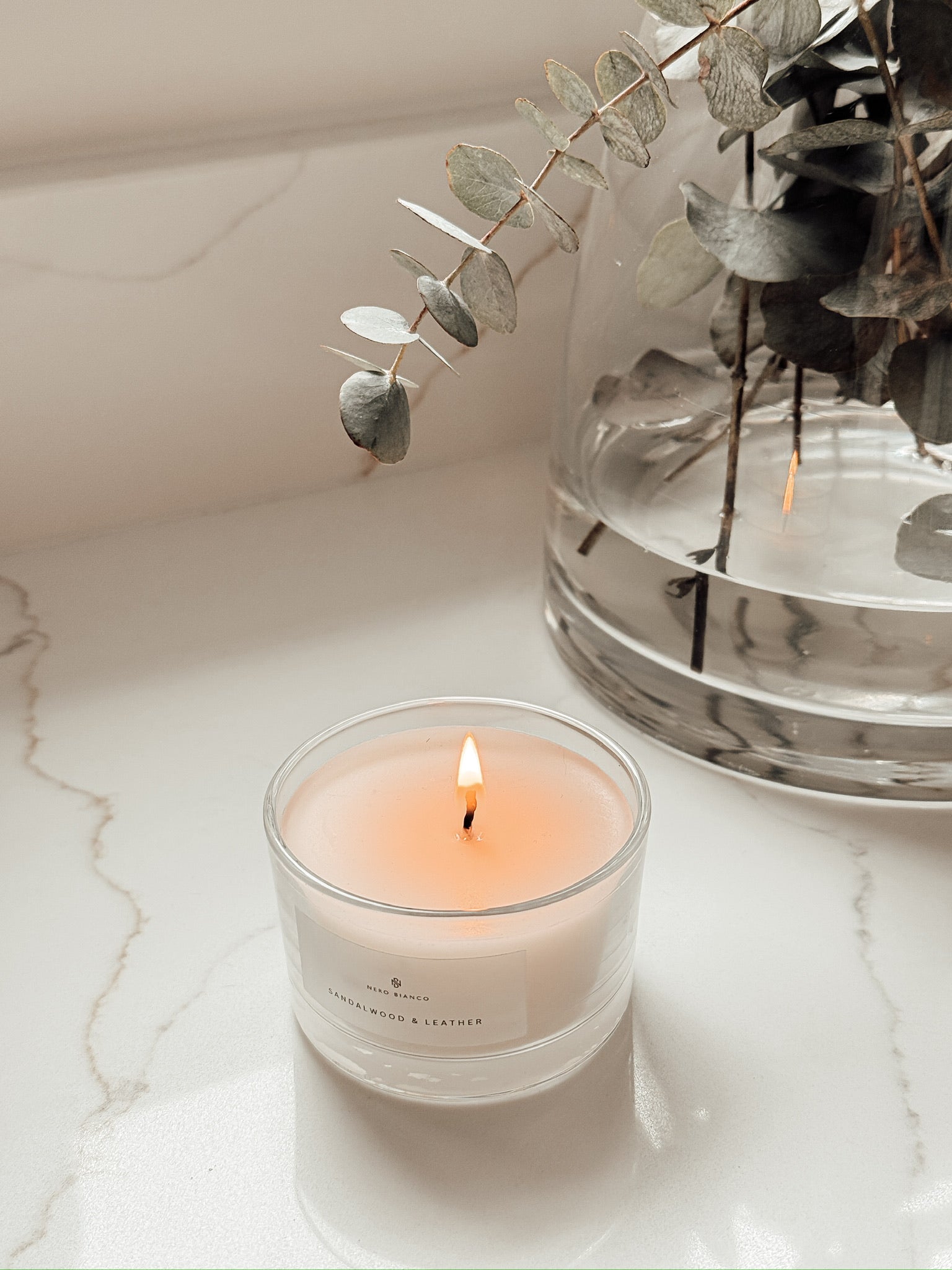 Votive Candle Sandalwood & Leather scented on neutral worktop with eucalyptus