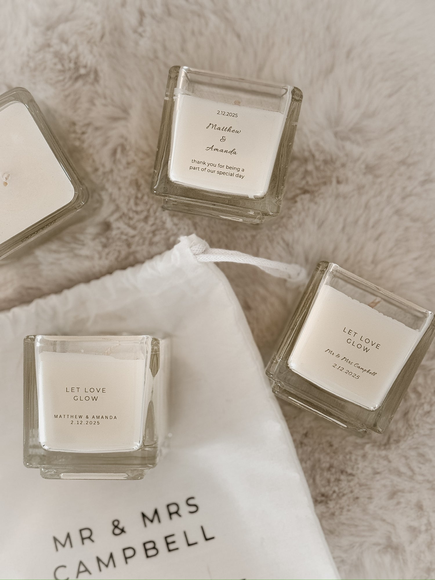 Four square candles with customised labels on for wedding favours